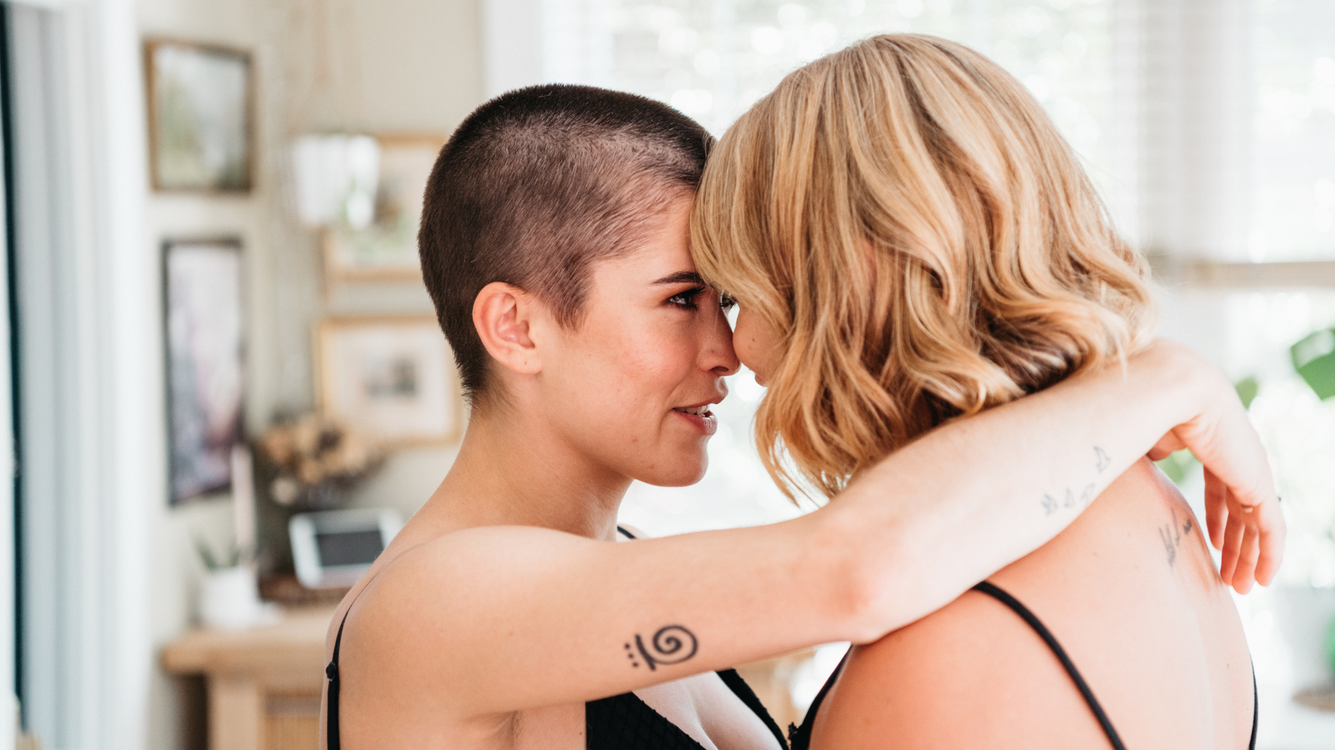 A lesbian couple standing close with their foreheads touching and looking into each other's eyes, representing love, lesbian dating, and LGBTQ+ connection.