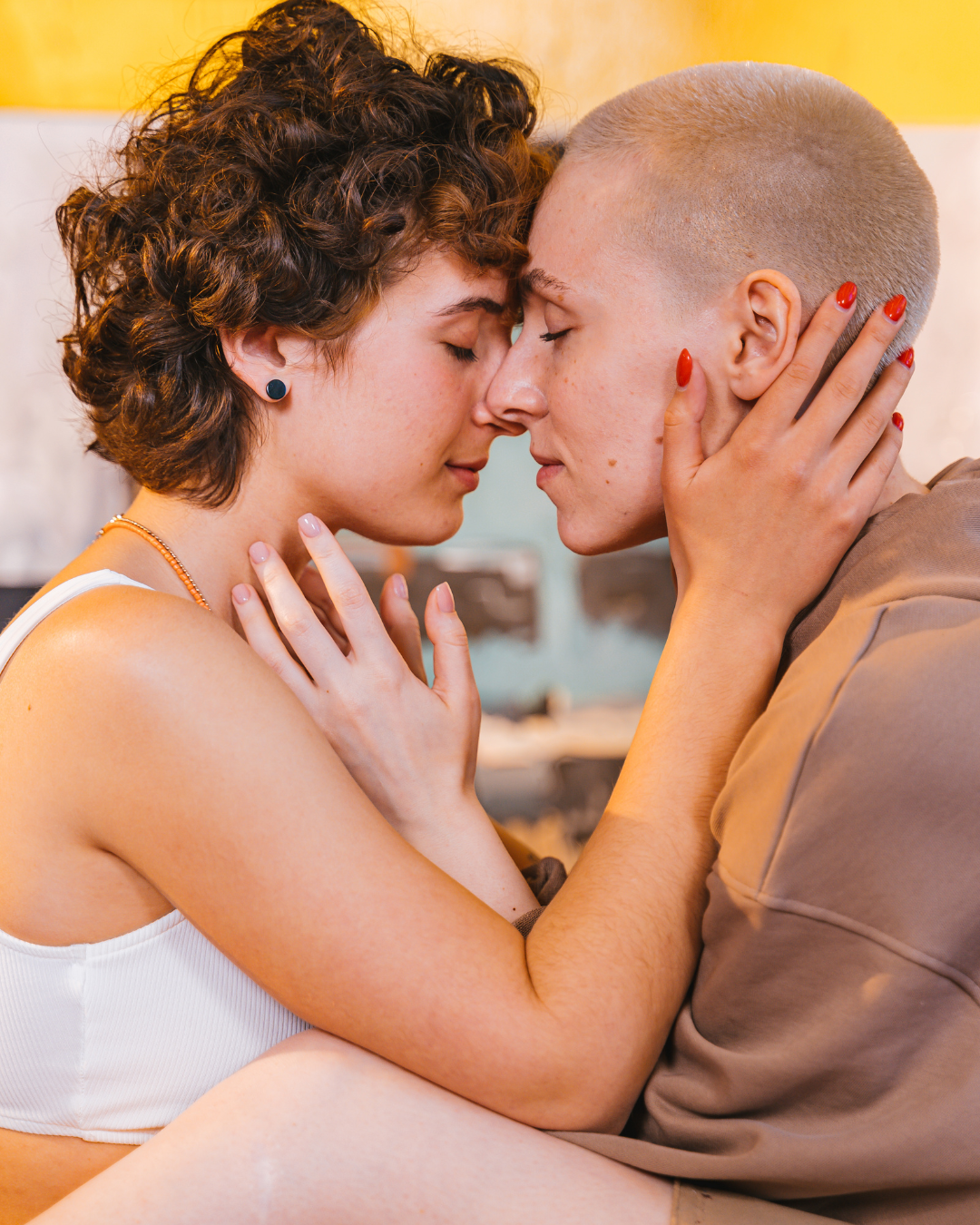 A lesbian couple sitting close together with their eyes closed, sharing a loving moment that celebrates lesbian dating and LGBTQ+ relationships.