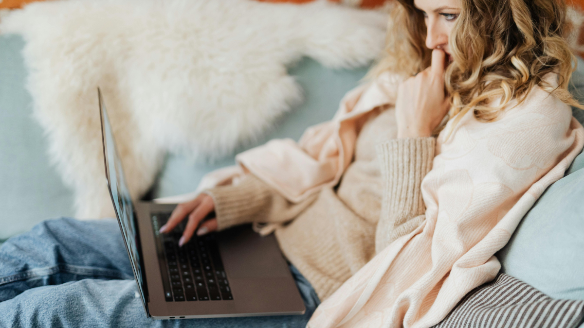 Queer woman using a laptop in bed while exploring sexuality and relationships online.