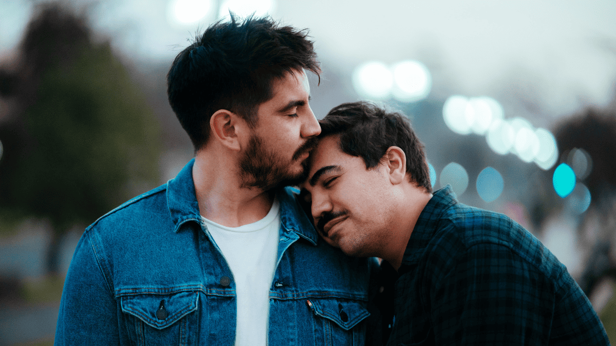 Two gay men sharing an affectionate moment outdoors while dating, representing LGBTQ+ matchmaking and meaningful relationships.